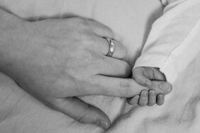 Babyhand hält Finger der Mama