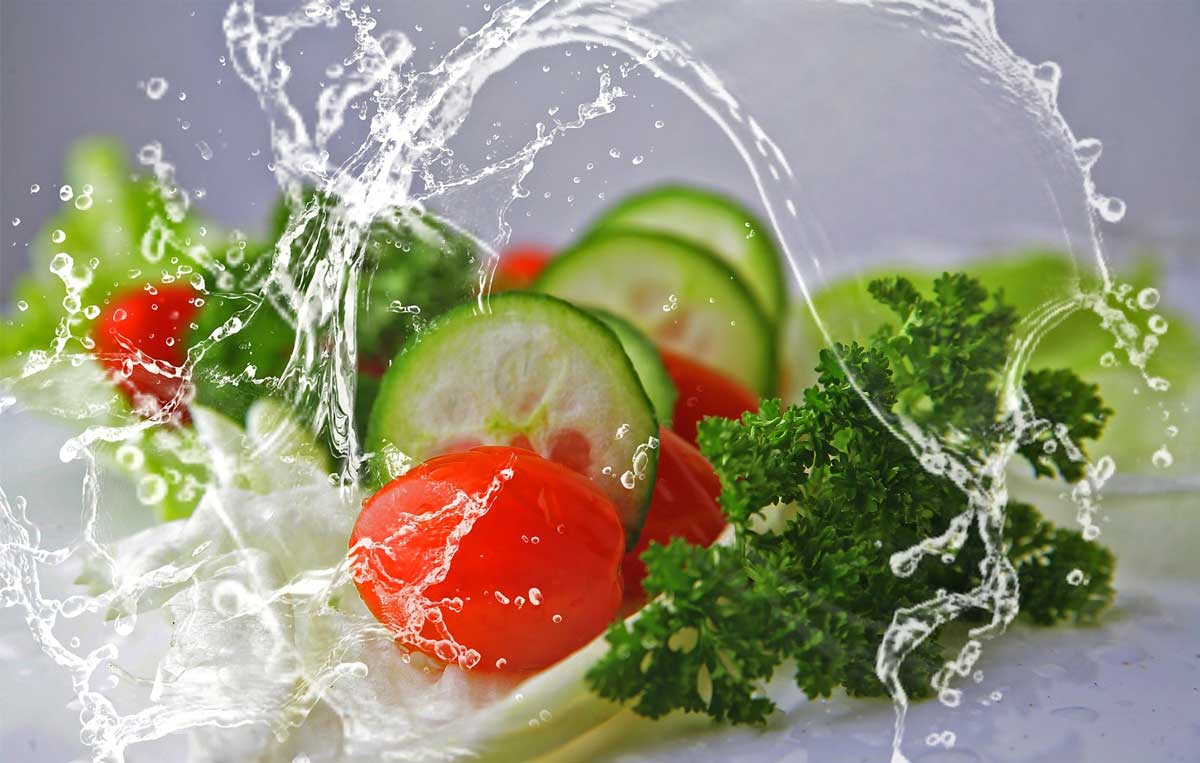 Salatgurgen, Tomaten und Petersilie werden von einem dynamischen Wasserspritzer umspielt
